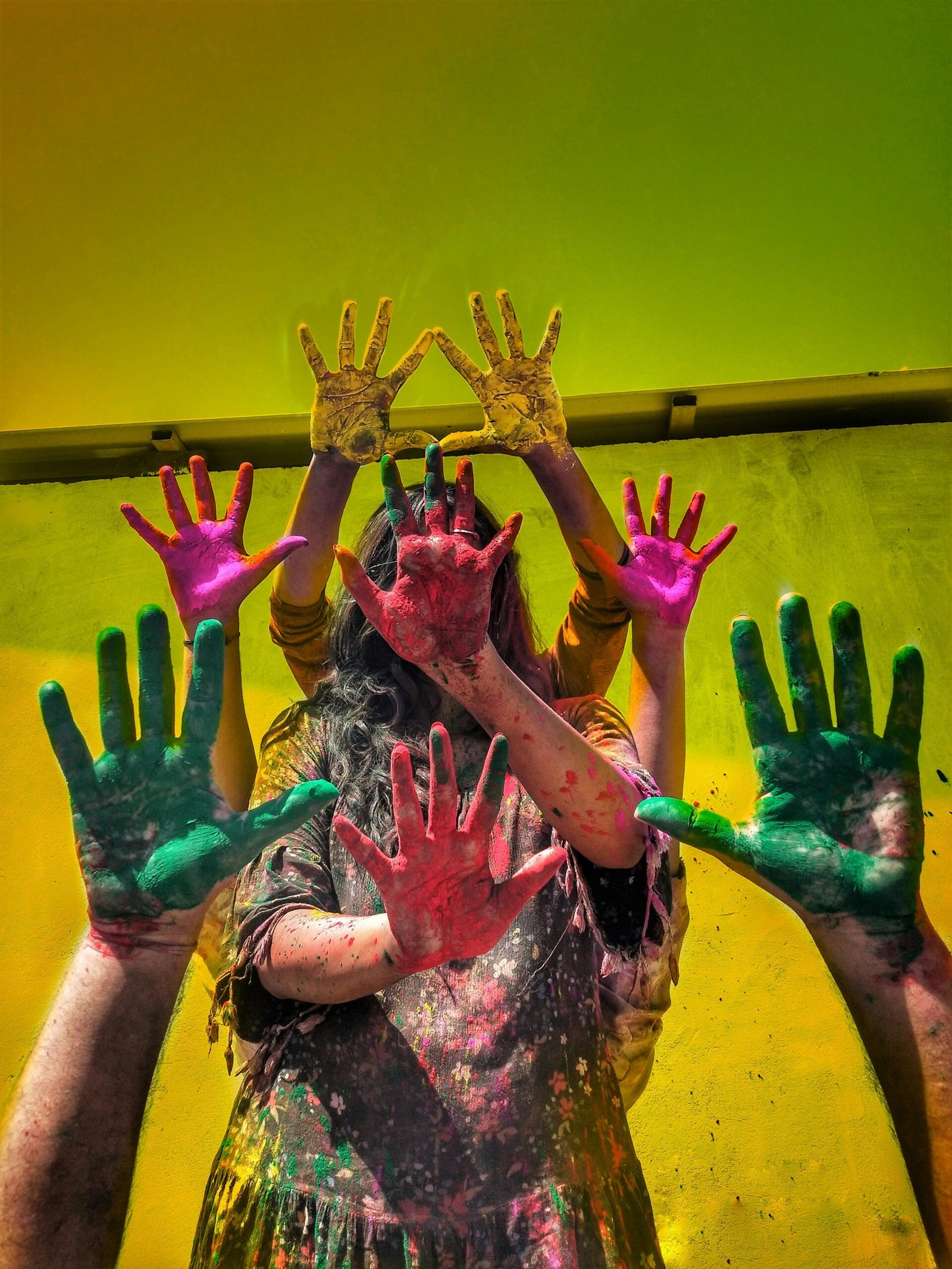 Group of people celebrating Holi with colorful painted hands and vibrant background.