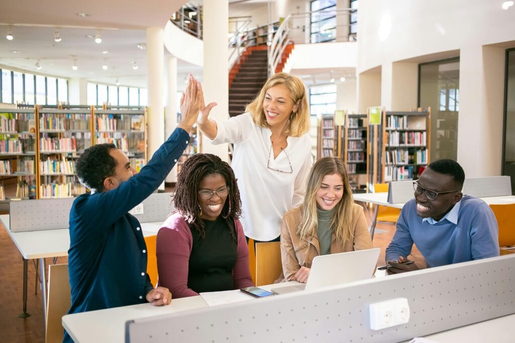 Cheerful diverse group of students collaborating in a library, celebrating with a high five.