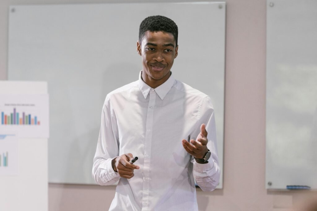 A confident young man presenting in a business setting, engaging with an audience.